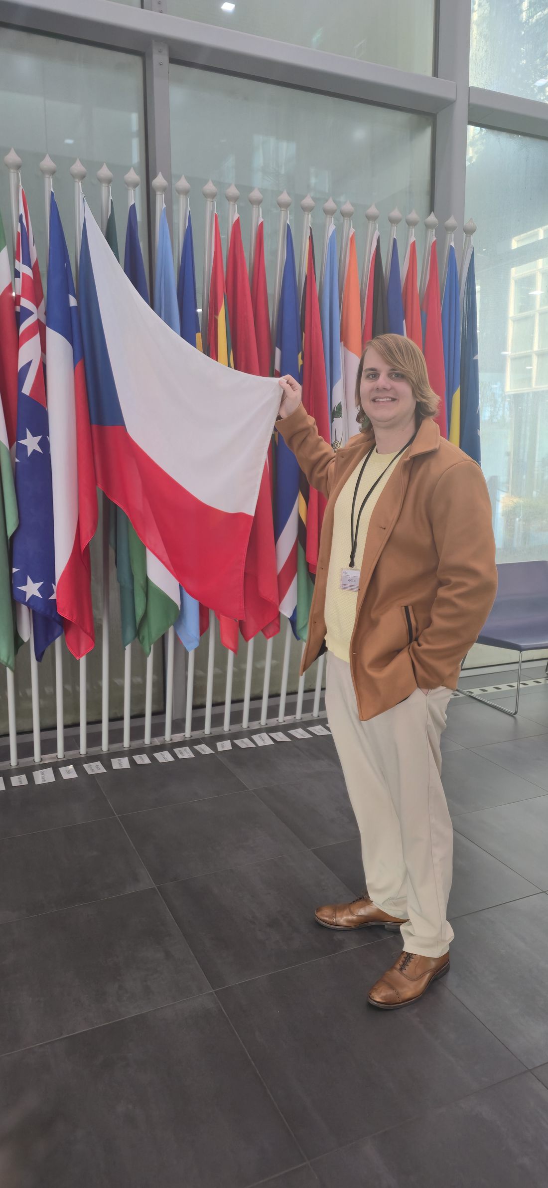 Adam Hanzel holding the Czech flag among a row of national flags